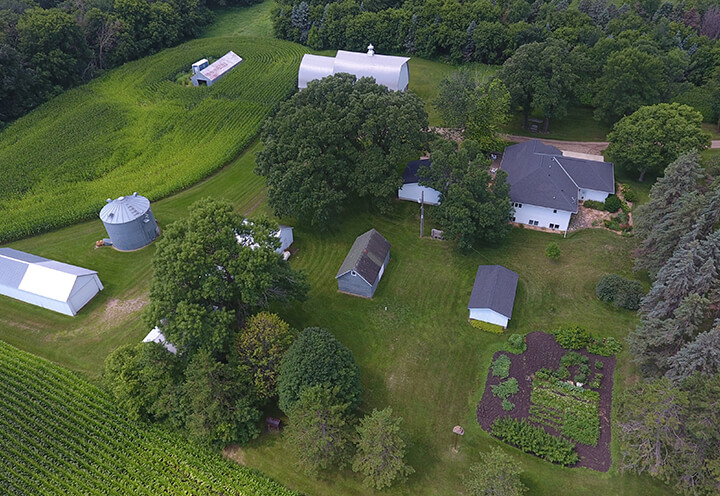 Aerial view of a Minnesota family farm with a house, out buildings, silo, and crop land | Farm Insurance